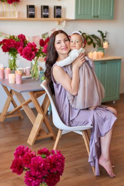 Anne ve kızı mutfakta zarif elbiseler peonies ile dekore edilmiş