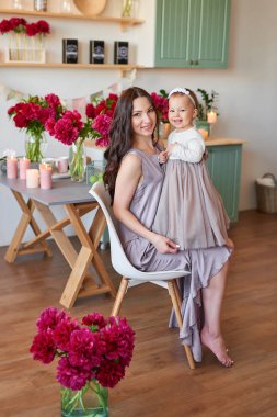 Anne ve kızı mutfakta zarif elbiseler peonies ile dekore edilmiş