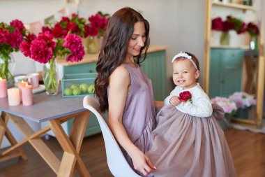 Anne ve kızı mutfakta zarif elbiseler peonies ile dekore edilmiş