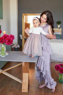 Anne ve kızı mutfakta zarif elbiseler peonies ile dekore edilmiş