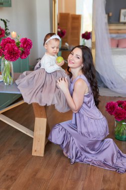 Anne ve kızı mutfakta zarif elbiseler peonies ile dekore edilmiş