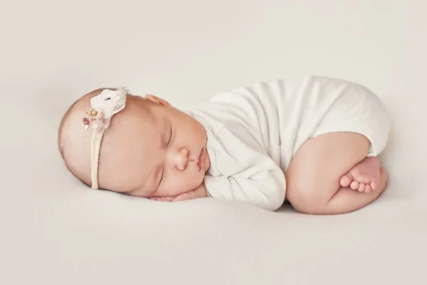 Yeni doğmuş tatlı bir kız bebek beyaz bir battaniyeye sarılmış yatıyor. Bebek eşyaları paketleme şablonu. Yüzünde gülümseme olan yeni doğmuş bir bebeğin yakın plan portresi. Sağlıklı ve tıbbi konsept. 