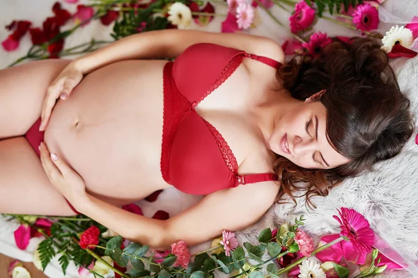 Schwangere Mädchen Roten Dessous Auf Einem Hintergrund Aus Blumen — Stockfoto