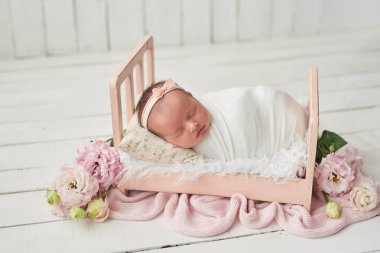 Yeni doğan kız yatakta beyaz bir arka plan üzerinde