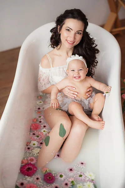 母亲和女儿在牛奶浴与鲜花 — 图库照片