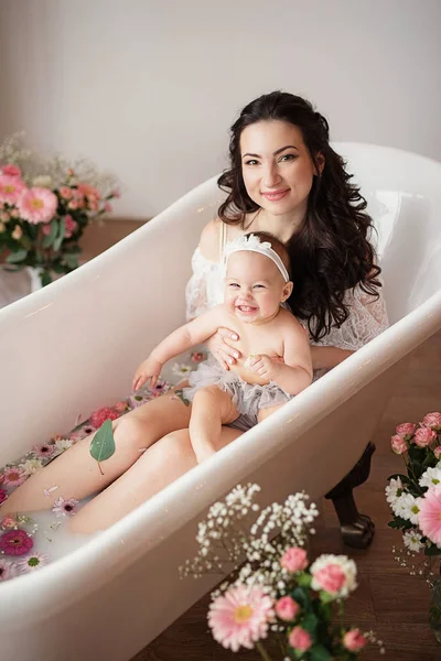 mother and daughter in a milk bath with flowers