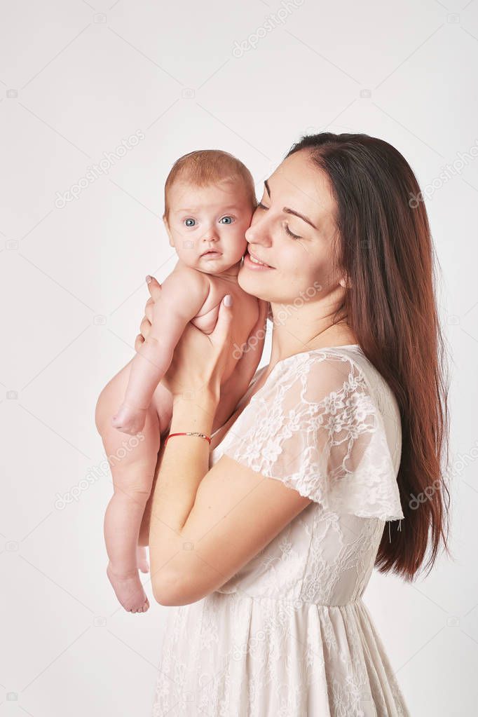young mother with natural make-up holds the baby in her arms, shot on a light background