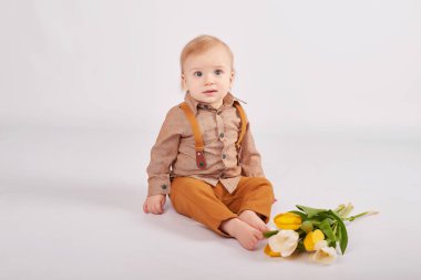 bir buket çiçek ile hafif bir arka plan üzerinde şirin yürümeye başlayan çocuk