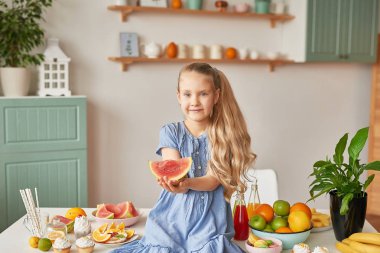The girl eats fruit pineapple, watermelon, apples and drinks drinks from chia. Healthy food in the children's menu