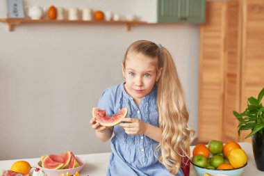 The girl eats fruit pineapple, watermelon, apples and drinks drinks from chia. Healthy food in the children's menu