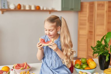 The girl eats fruit pineapple, watermelon, apples and drinks drinks from chia. Healthy food in the children's menu