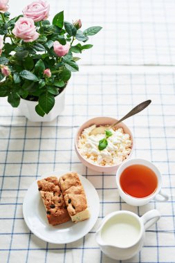 güveç, süzme peynir, çay süt ve tablo pencerenin karşısında üzerinde bir tencerede pembe güller