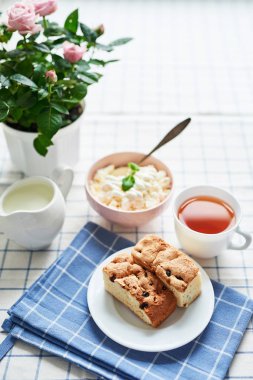 güveç, süzme peynir, çay süt ve tablo pencerenin karşısında üzerinde bir tencerede pembe güller