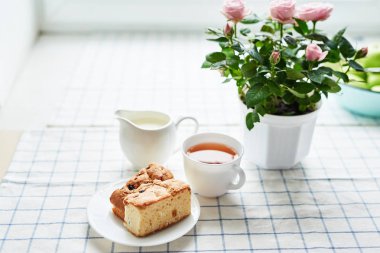 güveç, süzme peynir, çay süt ve tablo pencerenin karşısında üzerinde bir tencerede pembe güller