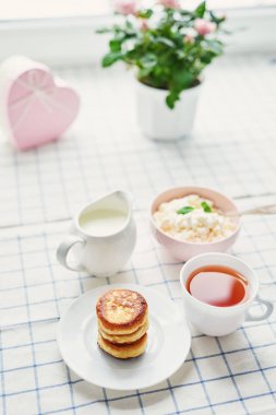 Cheesecakes ve tablo pencerenin karşısında çay süzme peynir