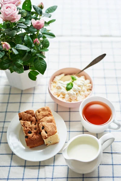 güveç, süzme peynir, çay süt ve tablo pencerenin karşısında üzerinde bir tencerede pembe güller