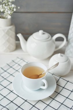 bir çaydanlık ve karanfil ahşap arka plan üzerinde bir vazo yanında bir fincan yeşil çay