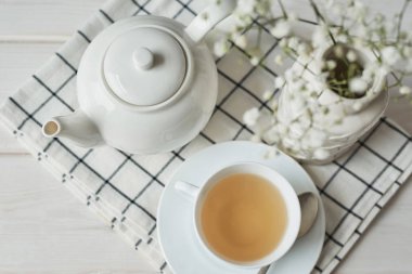 bir çaydanlık ve karanfil ahşap arka plan üzerinde bir vazo yanında bir fincan yeşil çay