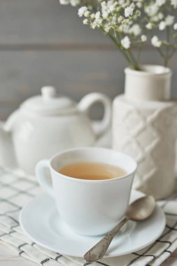 bir çaydanlık ve karanfil ahşap arka plan üzerinde bir vazo yanında bir fincan yeşil çay