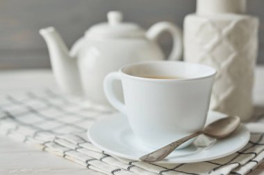 bir çaydanlık ve karanfil ahşap arka plan üzerinde bir vazo yanında bir fincan yeşil çay