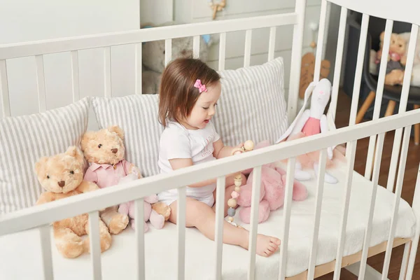 girl in a crib with toys in the children\'s room