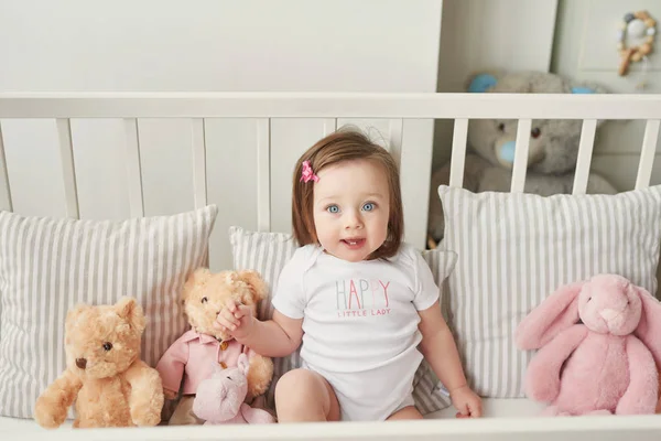 girl in a crib with toys in the children's room