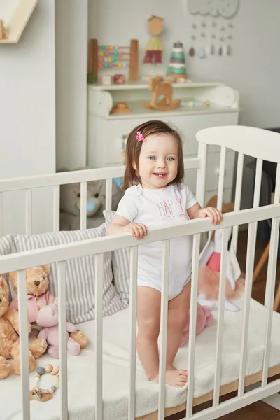 girl in a crib with toys in the children\'s room