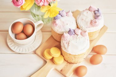 Masada Paskalya pastaları, macaroons, yumurta ve beyaz bir arka planda yakın bir vazo çiçek bir buket