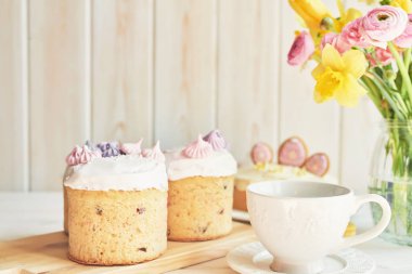 Masada Paskalya pastaları, macaroons, yumurta ve beyaz bir arka planda yakın bir vazo çiçek bir buket