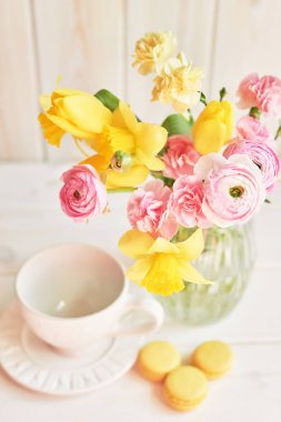 ahşap bir arka planda bahar çiçekleri bir buket ile bir vazo ile yakın fincan