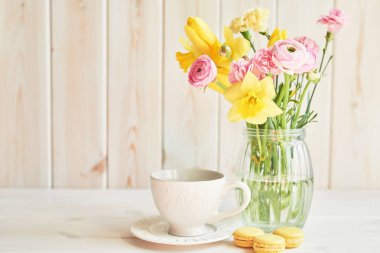 ahşap bir arka planda bahar çiçekleri bir buket ile bir vazo ile yakın fincan