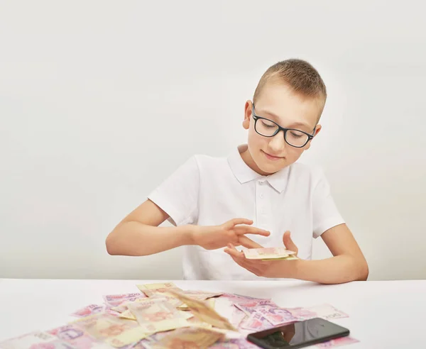 男孩与钱和笔记本电脑在白色背景的桌子上 — 图库照片