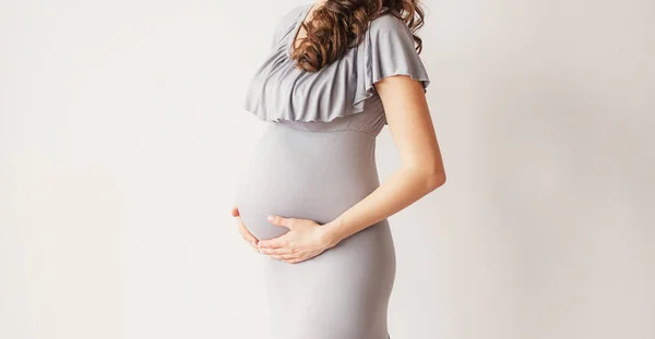 怀孕的女孩在一个光的背景 相框中没有人脸的照片 — 图库照片