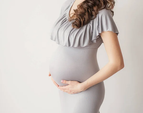 stock image Pregnant girl on a light background. Photo without a face in the frame.