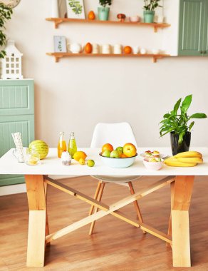 Fruits: apples, watermelon, pineapple, bananas, lemons, oranges on the table, warm loft-style kitchen