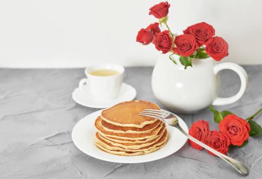 4 Temmuz 'da bağımsızlık günü, masada tabak ve kırmızı güller yanında Amerikan krep.