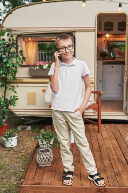 Tekerlekli evin yakınında yaz aylarında tatile bir telefon ile çocuk çocuk