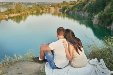 Göle yakın doğada genç çift günbatımı istirahat