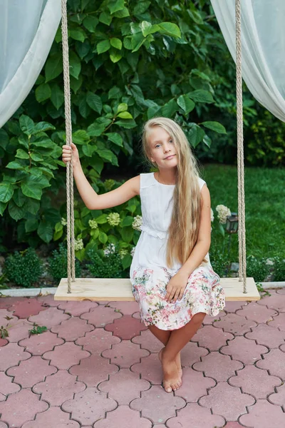 girl riding a swing in the summer in the garden