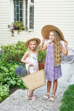 bir yazlık bahçede Lavanta bir sepet ile şapkalar iki bebek kız