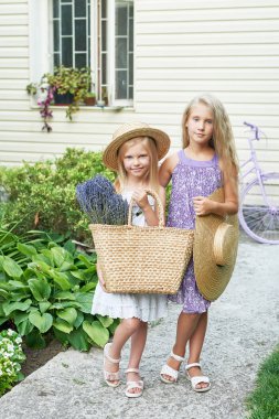 bir yazlık bahçede Lavanta bir sepet ile şapkalar iki bebek kız