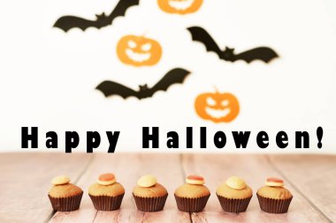 Cadılar Bayramı kabak ve yarasalar arka plan karşı masada cupcakes davranır