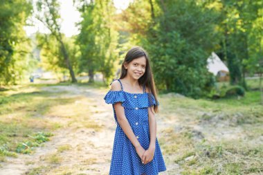 mavi elbiseli genç kız gün batımında yaz ormanında yürüyor