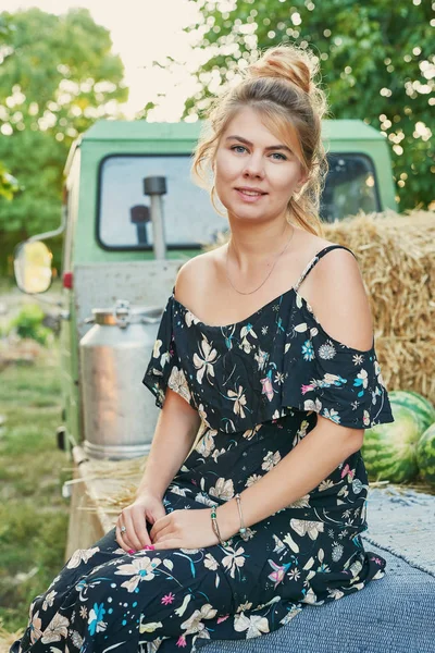harvesting, a girl near a pickup truck with watermelons in the summer at sunset