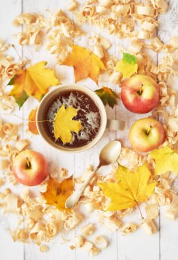 Sonbahar arkaplanında çay fincanı elma, yaprak ve çiçeklerle.