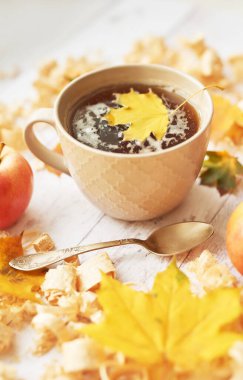 Sonbahar arkaplanında çay fincanı elma, yaprak ve çiçeklerle.