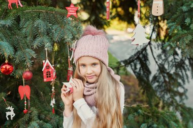 Temmuz 'da Noel ağacının yanında şapkalı ve atkılı bir çocuk.