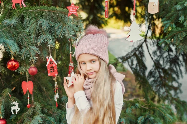 child girl in a hat and scarf near the Christmas tree, Christmas in July