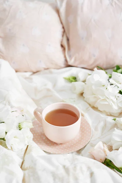 Breakfast in bed in hotel room. Accommodation. Breakfast in bed with tea cup and flowers on bed background top view. Copy Space. Romantic valentine\'s day breakfast. Cozy morning. Happy Mother\'s Day.