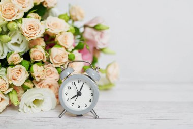 Sıcak bir sabah. Anneler günü çiçek kartı. Bir buket çiçek ve çalar saat. İyi sabahlar. Kadın Günü için yaratıcı bir kahvaltı. Uzayı kopyala Paskalya baharı hayat sahnesi. Kahve kupası. Zaman kavramı.